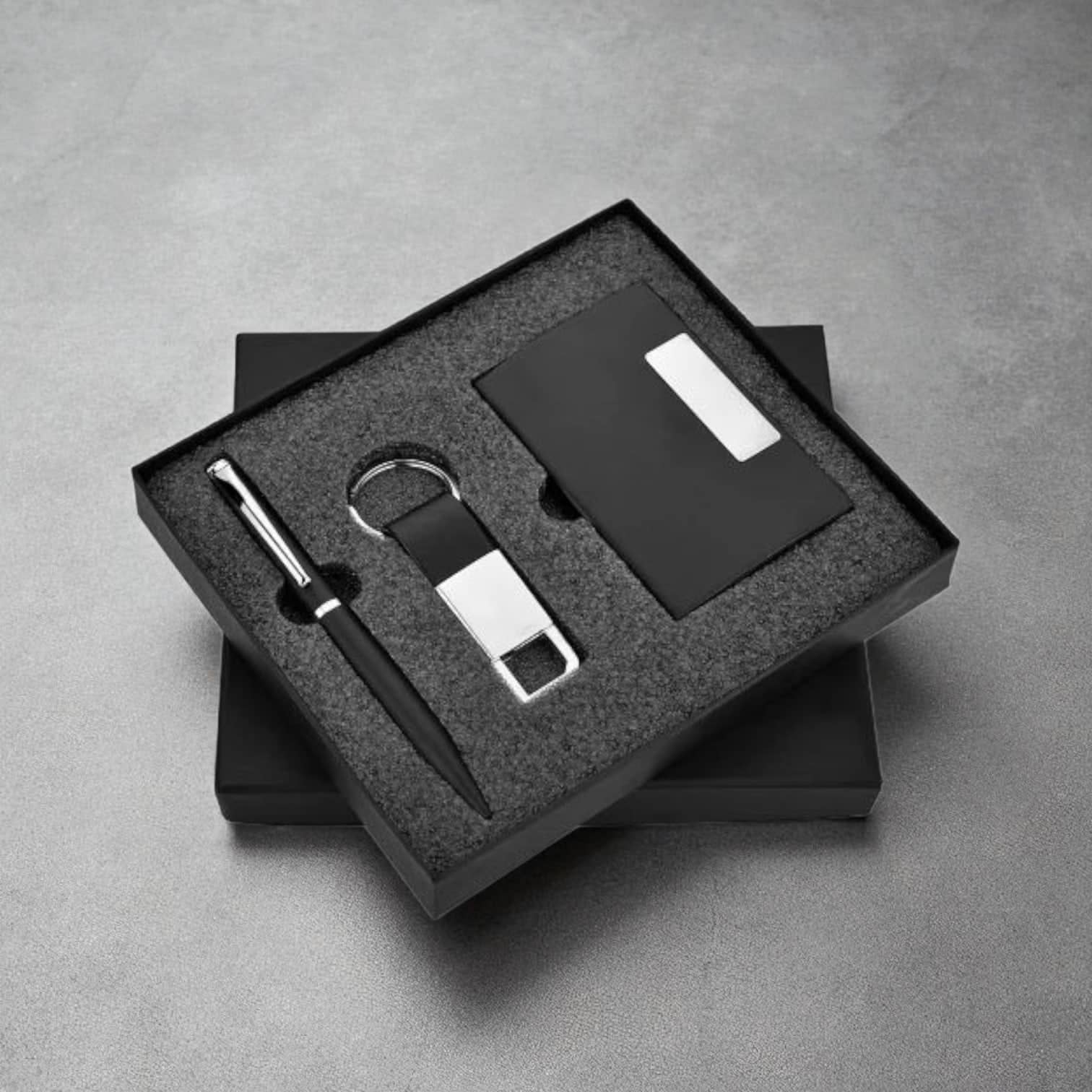 PackSmart black two-piece gift box with a foam insert holding a pen, a metal keyring and a card holder.