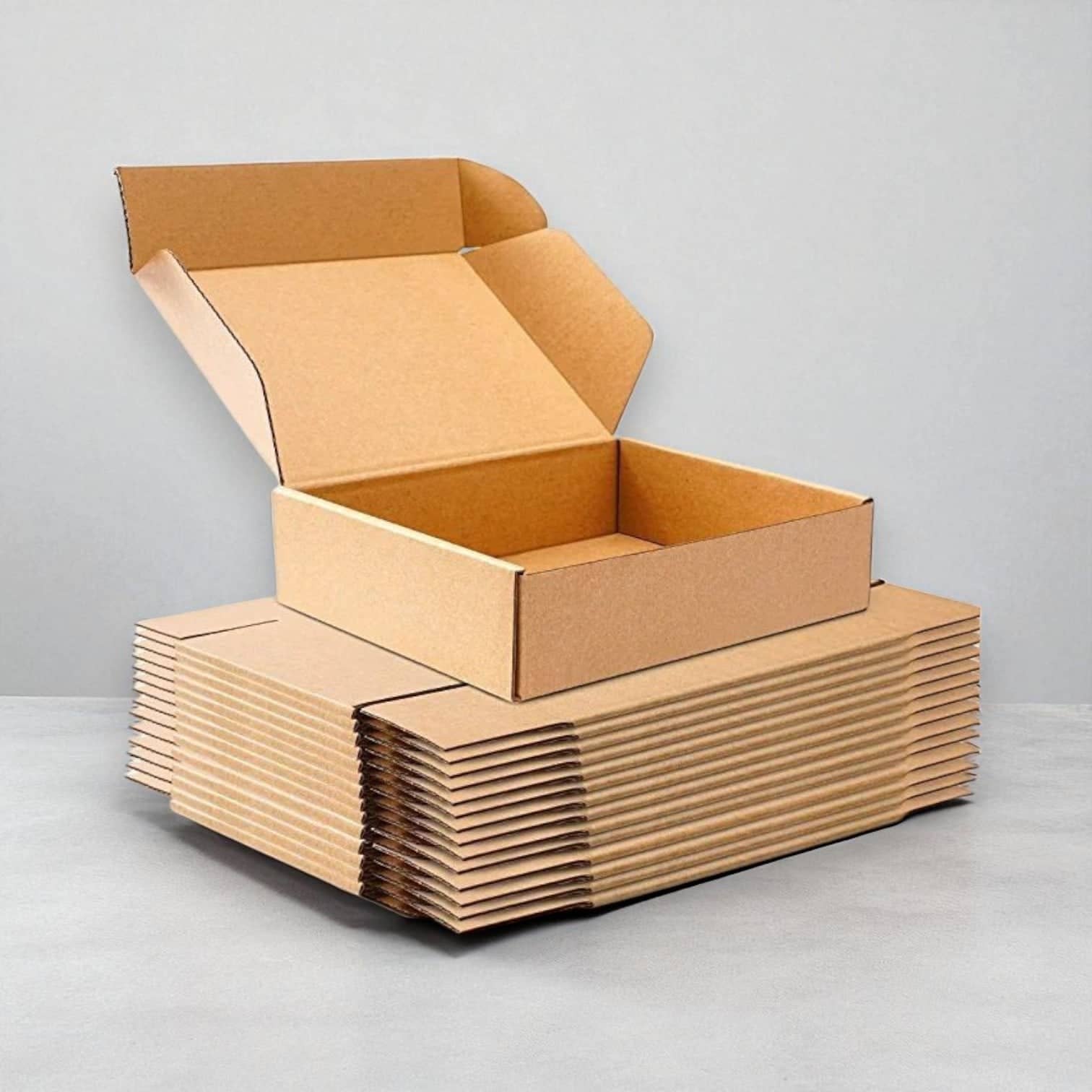 PackSmart open kraft corrugated mailer box on a stack of flat mailers.