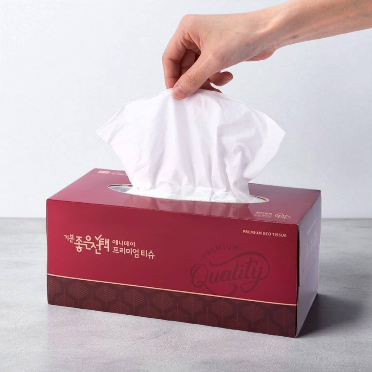 PackSmart deep red printed tissue box with a hand pulling a tissue from the opening.